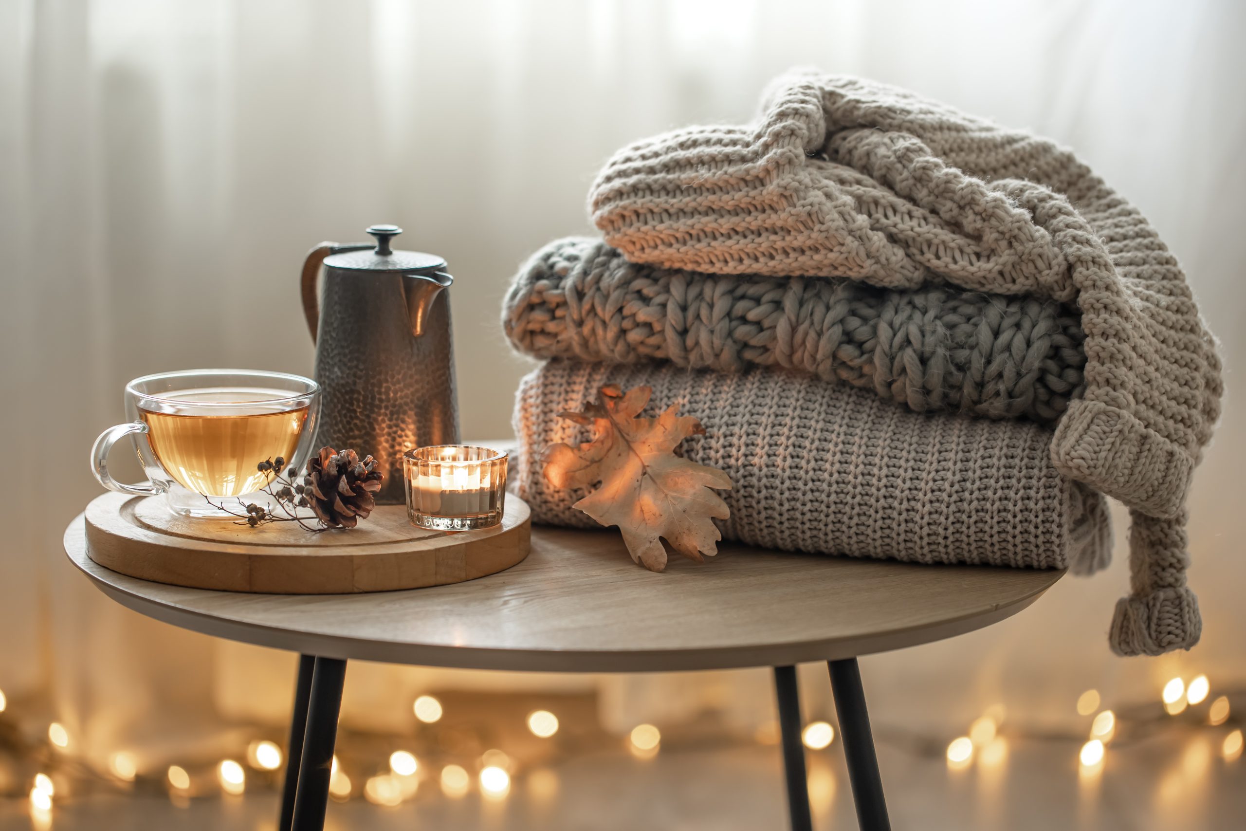 Útulné domáce jesenné dekorácie s teplým čajom a vlnená deka.